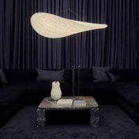 Elegant white pendant light above a dark sofa and marble coffee table, with rich navy curtains in the background.