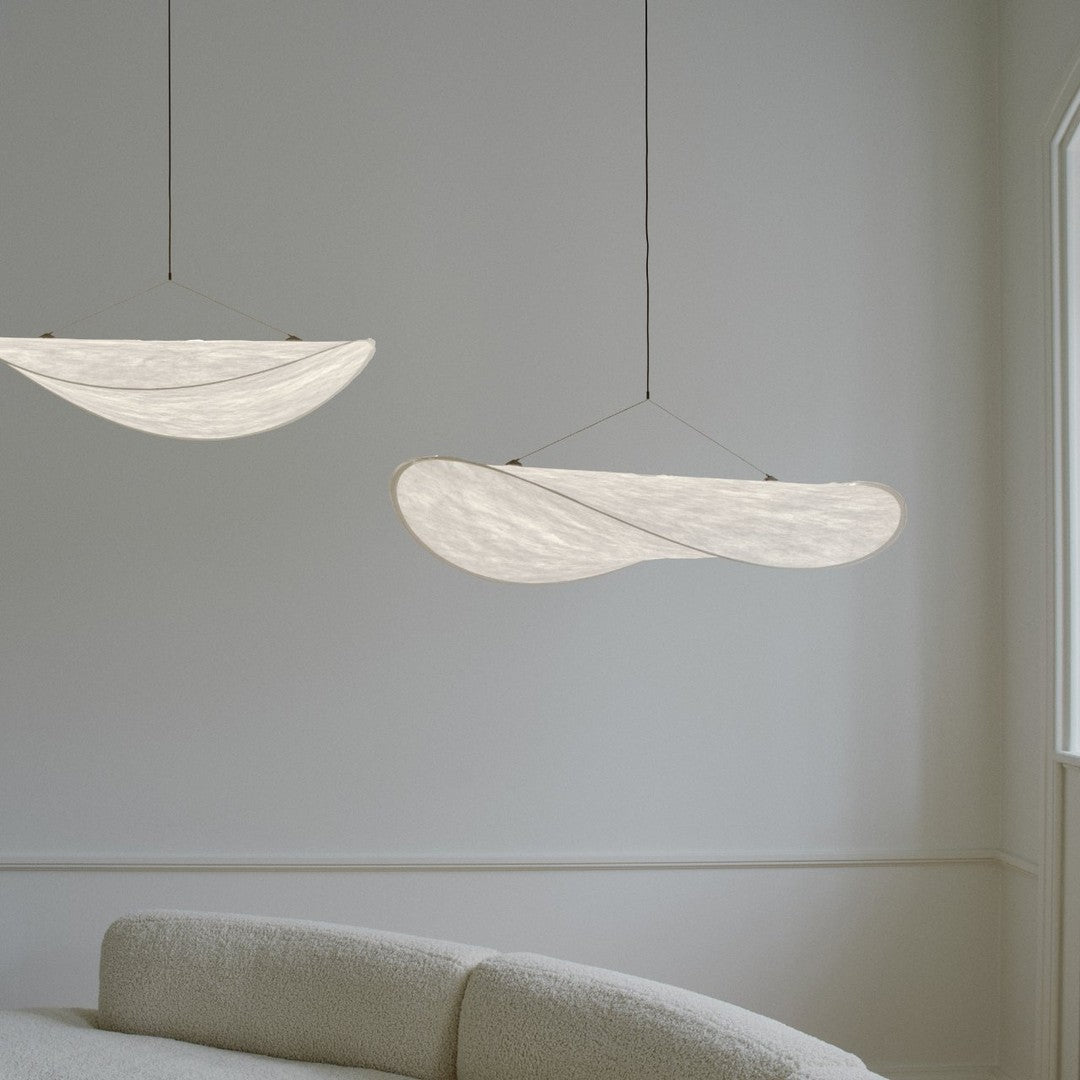 "Two soft white, curved pendant lights with a subtle, textured pattern, hanging elegantly in a minimalist interior."