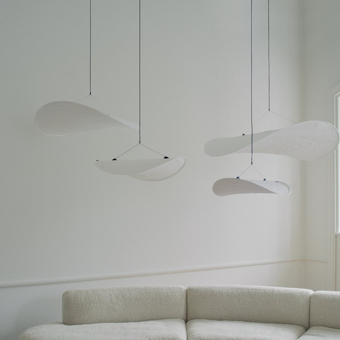 Modern white hanging light fixtures with sleek, curved shapes against a neutral background, enhancing minimalist decor.