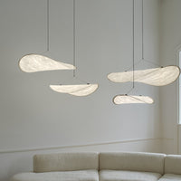 "Modern pendant lights in soft white with organic, flowing patterns, suspended over a light-colored sofa."