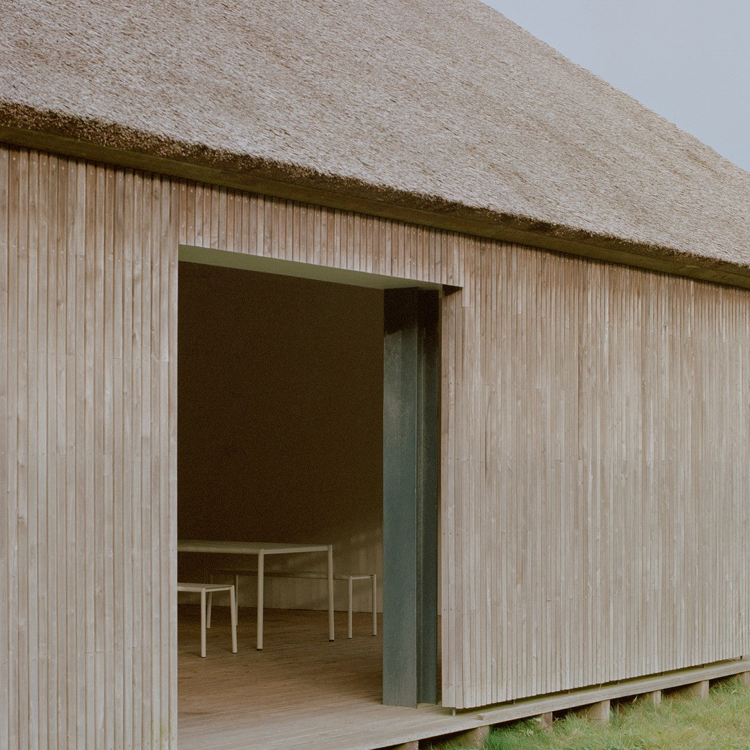 "Natural wood tones with a textured straw roof; green door adds a pop of color to the rustic exterior."