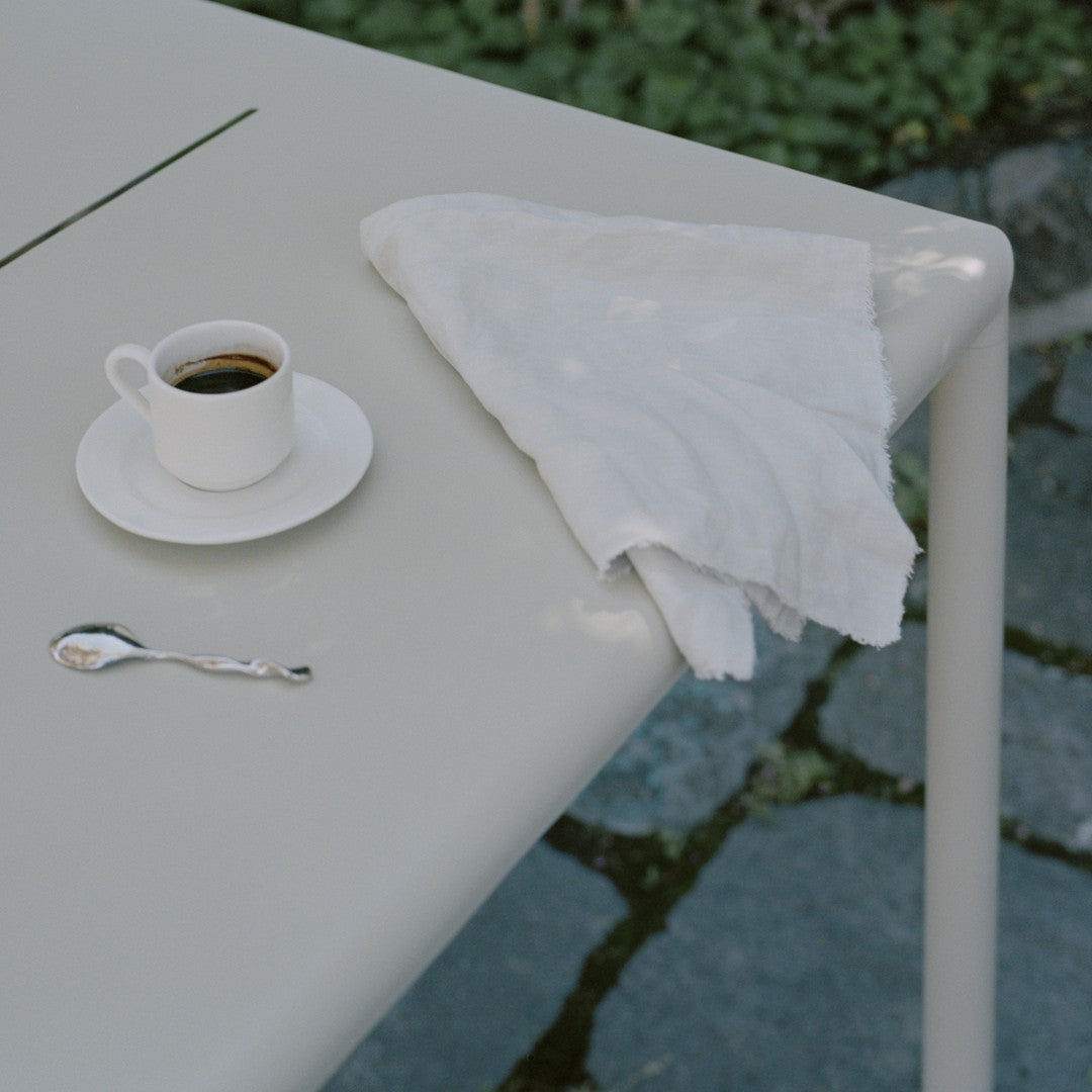 Light gray table surface with a white napkin and fine china cup, set against a stone background.