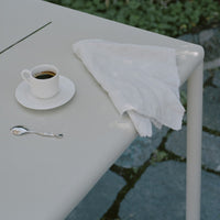 Light gray table surface with a white napkin and fine china cup, set against a stone background.