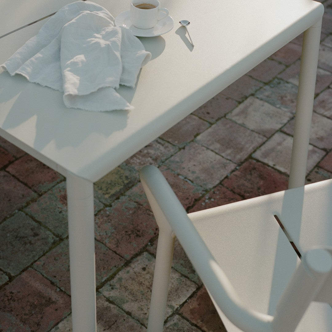 Stylish white modern table and chair set on a rustic brick pattern background, featuring soft shadows and textures.