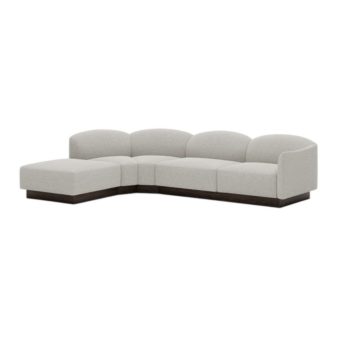 Light gray sectional sofa with smooth curves and a sleek, dark wood base for a modern aesthetic.