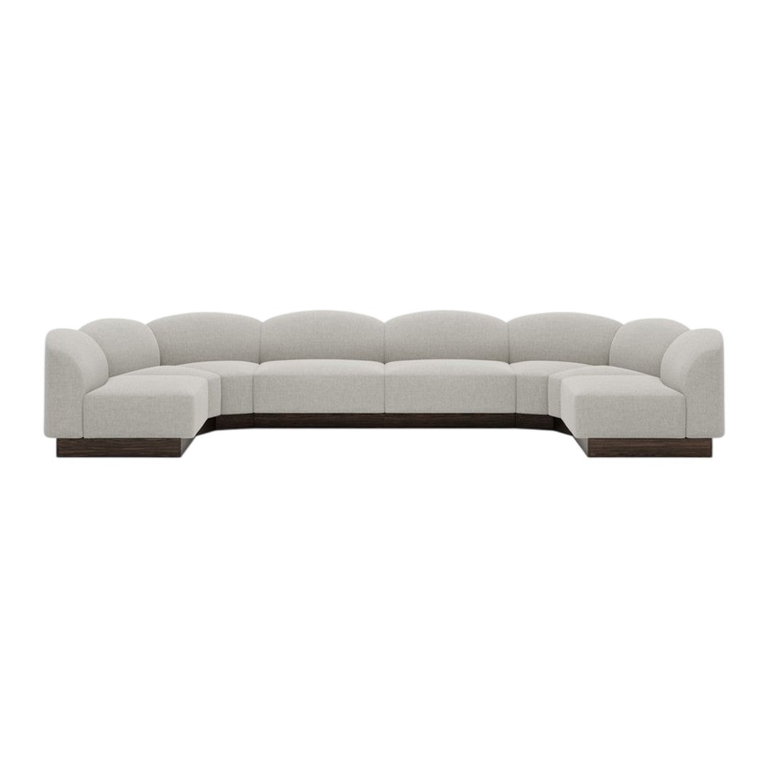 Luxe curved sectional sofa in soft beige upholstery with a sleek dark wood base. Modern, minimalist design.