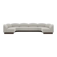 Luxe curved sectional sofa in soft beige upholstery with a sleek dark wood base. Modern, minimalist design.