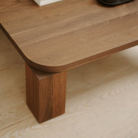 "Natural wood coffee table with smooth, rounded edges and warm brown tones, showcasing a minimalist design."