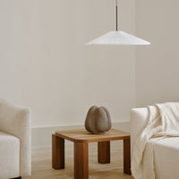 Stylish white pleated pendant lamp above a wooden table, complementing neutral tones of the light sofa and decor.