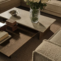 Modern beige coffee table with minimalistic design and textured wood finish, complemented by soft, neutral-toned furnishings.