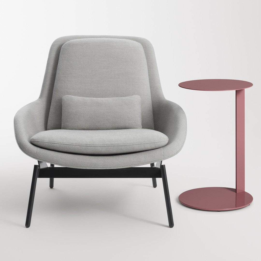 Gray upholstered chair with a black frame and pink side table featuring a round top, sleek modern design.