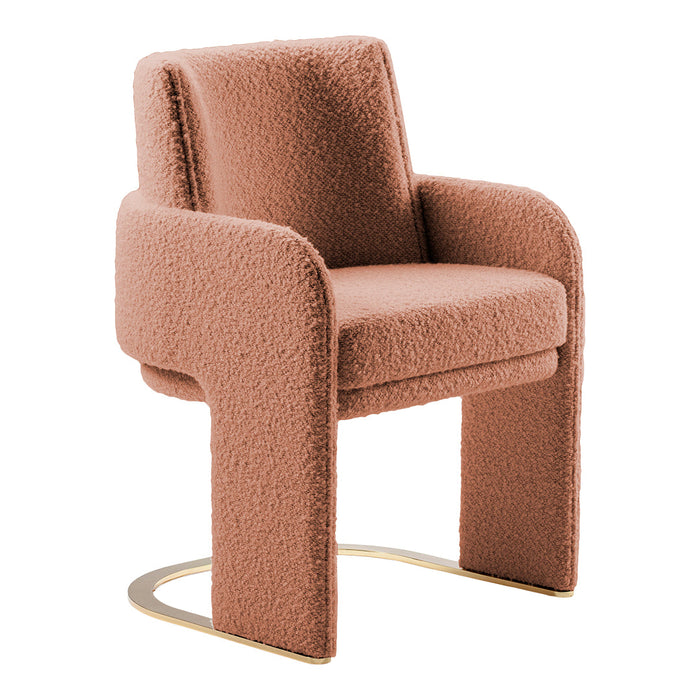 Soft pink textured upholstered chair with sleek gold base, featuring a modern, minimalist design.