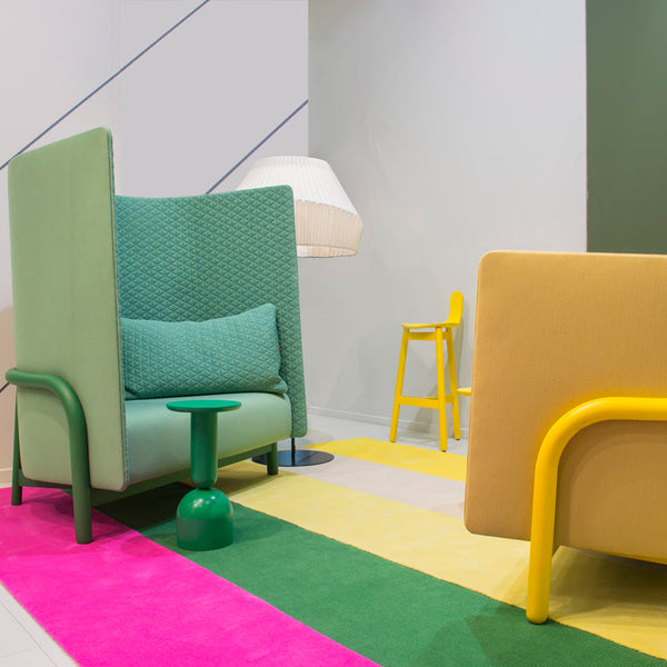 Colorful lounge area featuring a green and yellow patterned rug, vibrant furniture in green, pink, and yellow tones.