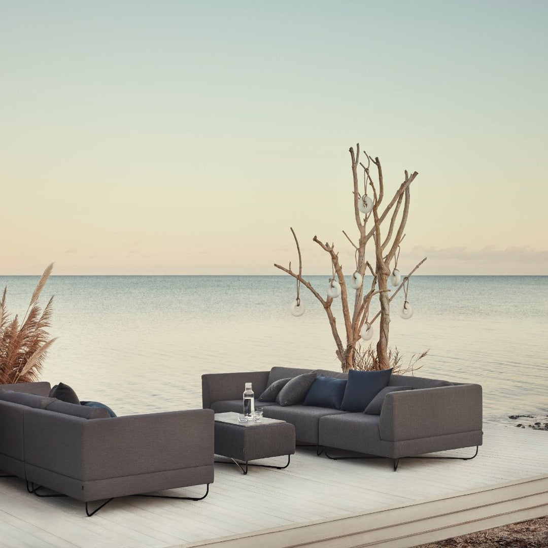 Modern dark gray outdoor lounge set with sleek lines, complemented by a minimalist, serene background of soft hues.