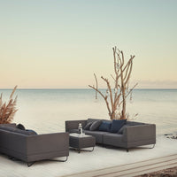 Modern dark gray outdoor lounge set with sleek lines, complemented by a minimalist, serene background of soft hues.