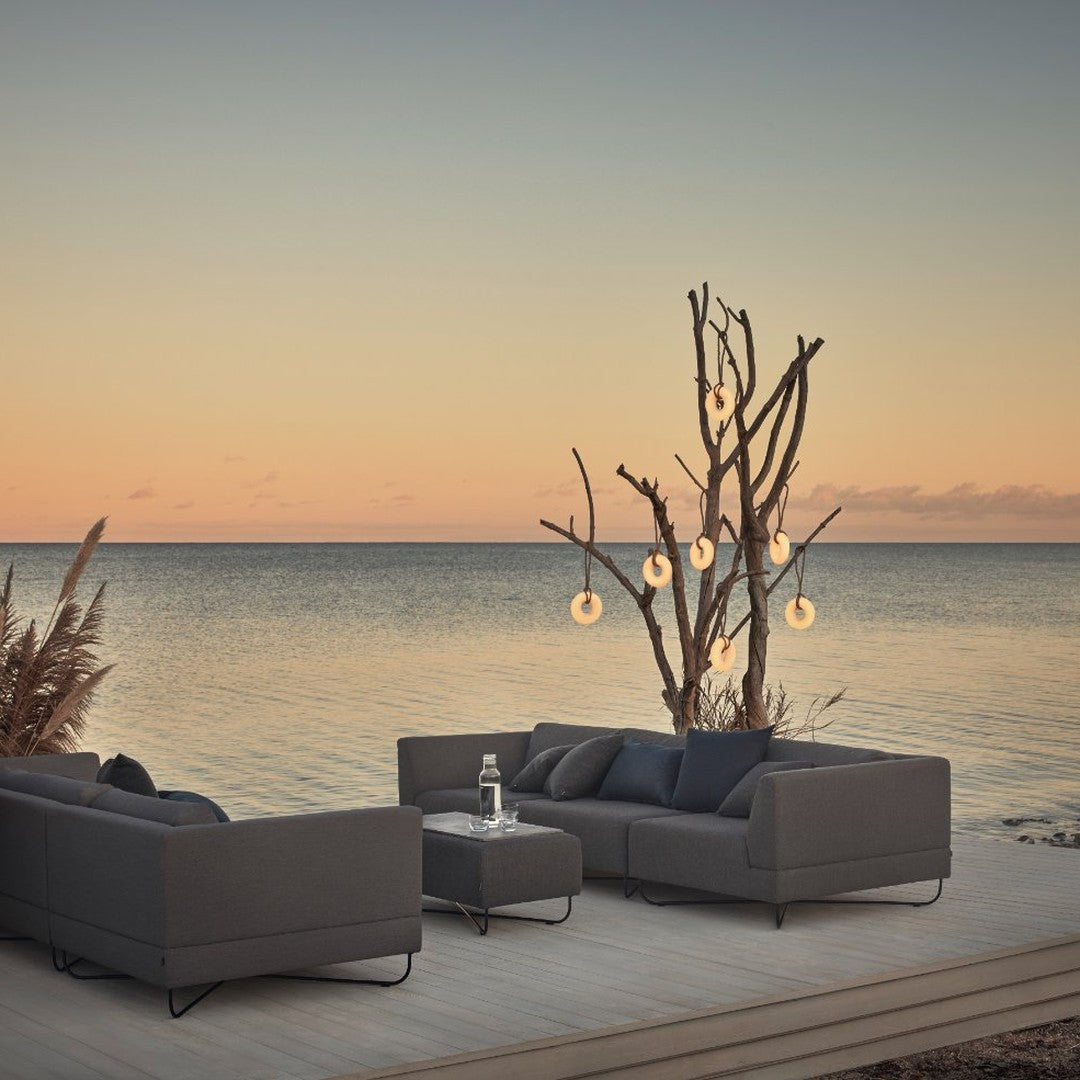 Sleek gray outdoor sofa set with subtle patterns, complemented by a serene sunset and natural accents.