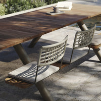 Natural wood table with gray woven fabric chairs, featuring a modern design and warm earthy tones. Perfect for outdoor settings.