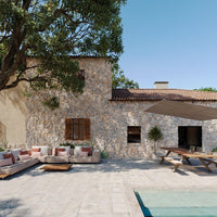 "Textured stone wall, warm terracotta roof, soft beige sofa with earthy cushion colors, clear blue sky backdrop."