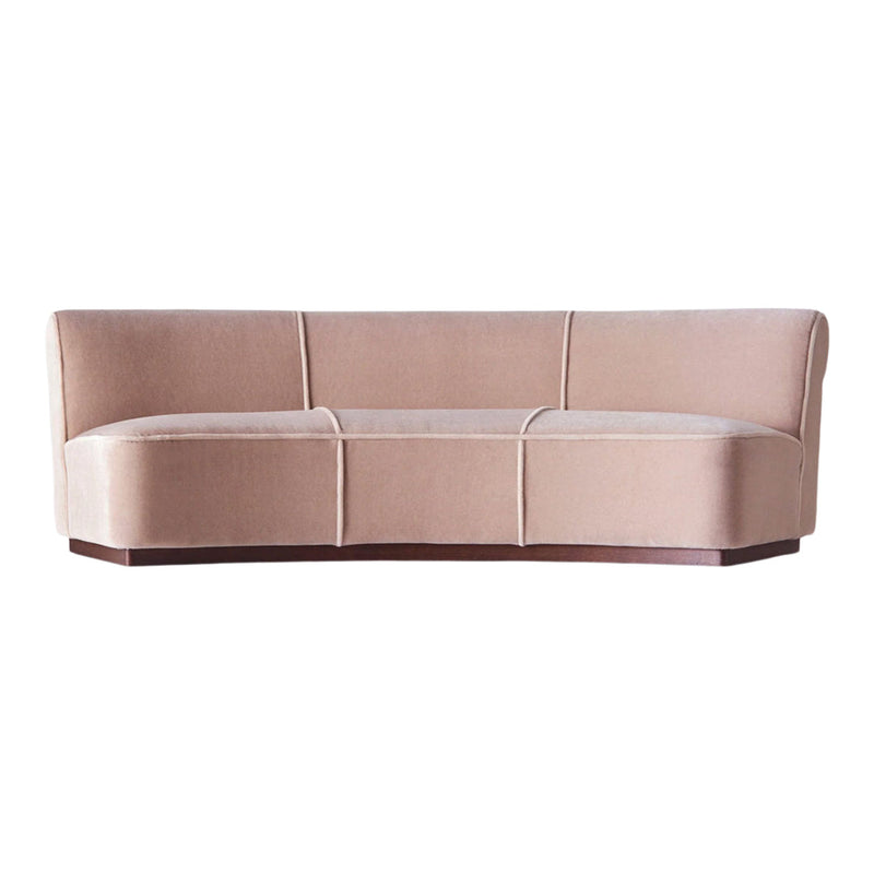 Blush pink velvet sofa with smooth, curved lines and subtle stitching details, perfect for modern interiors.