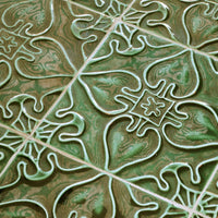 Green patterned ceramic tiles with intricate floral designs and glossy finish. Perfect for stylish interiors.