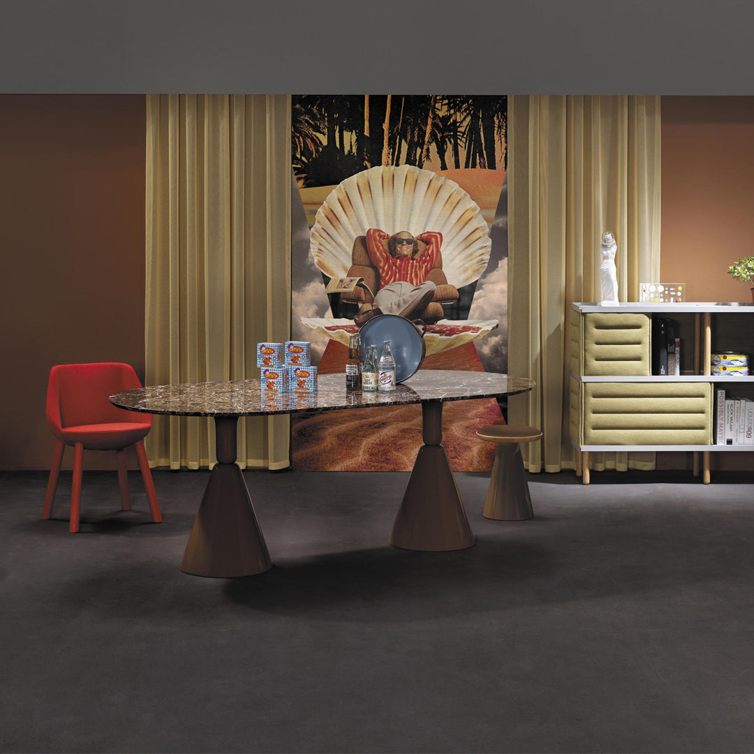 Modern dining room featuring a marbled table, vibrant red chair, golden curtains, and earthy brown tones.