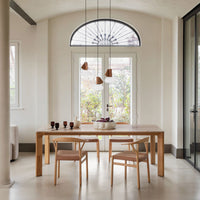 Elegant wooden dining table with soft beige chairs, featuring neutral tones and geometric light fixtures.