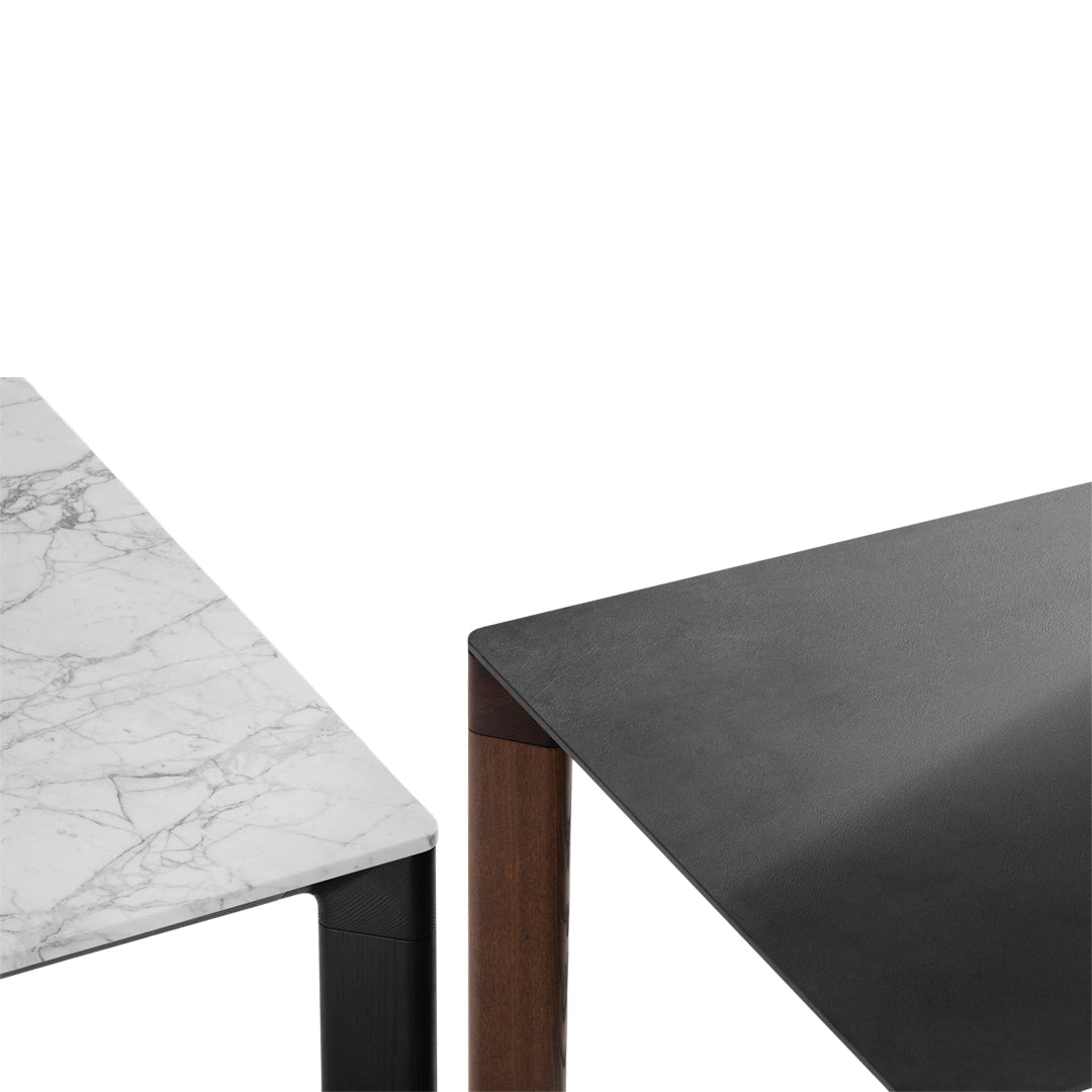 Marble and sleek black table surfaces with contrasting wood accents, showcasing elegant modern design.