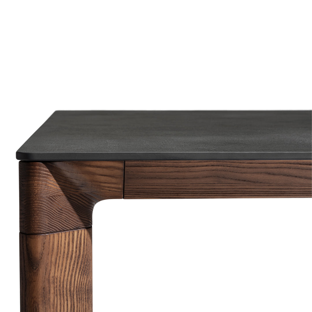 Modern wooden table with a dark black top and rich brown textured legs, showcasing a sleek design and natural patterns.