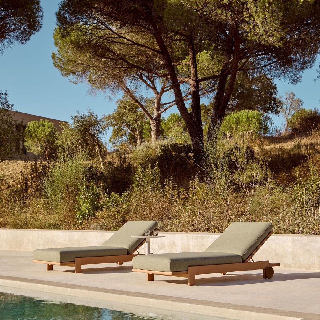 "Two olive green lounge chairs with wooden frames beside a tranquil pool, surrounded by greenery."
