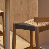 Natural wood barstool with a woven beige pattern against a warm, minimalistic backdrop. Stylish and modern design.