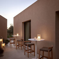 "Light beige walls, white tabletops, and natural wood furniture create a serene outdoor setting."