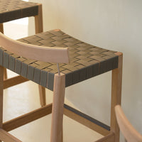 Woven grey and brown pattern on a stylish wooden bar stool seat. Modern design with natural wood finish.