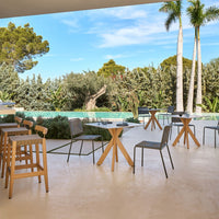 Outdoor dining set featuring natural wood tones and gray fabric, complemented by a serene green landscape.