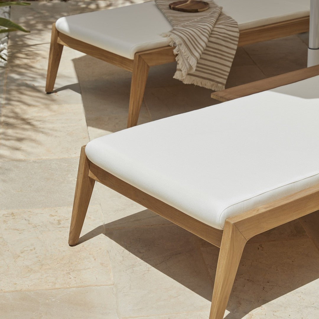 White cushioned lounge chairs with natural wood legs, set against a light stone floor and striped beige accents.