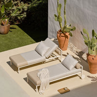 "Beige and white striped outdoor lounge chairs with soft cushions in a vibrant plant-filled setting."