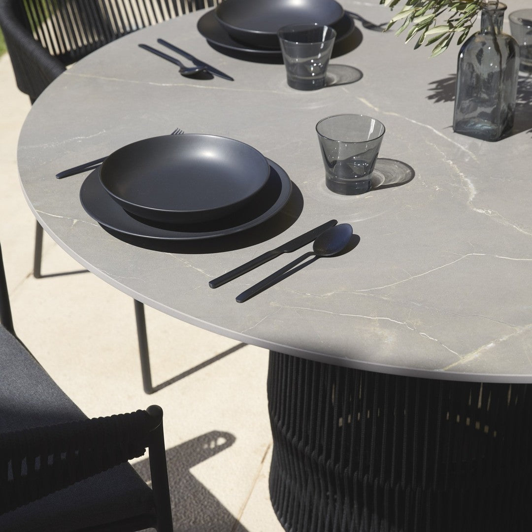 Stylish gray marble tabletop with black plates and glassware, featuring sleek modern patterns and textures.