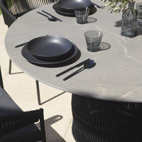 Stylish gray marble tabletop with black plates and glassware, featuring sleek modern patterns and textures.