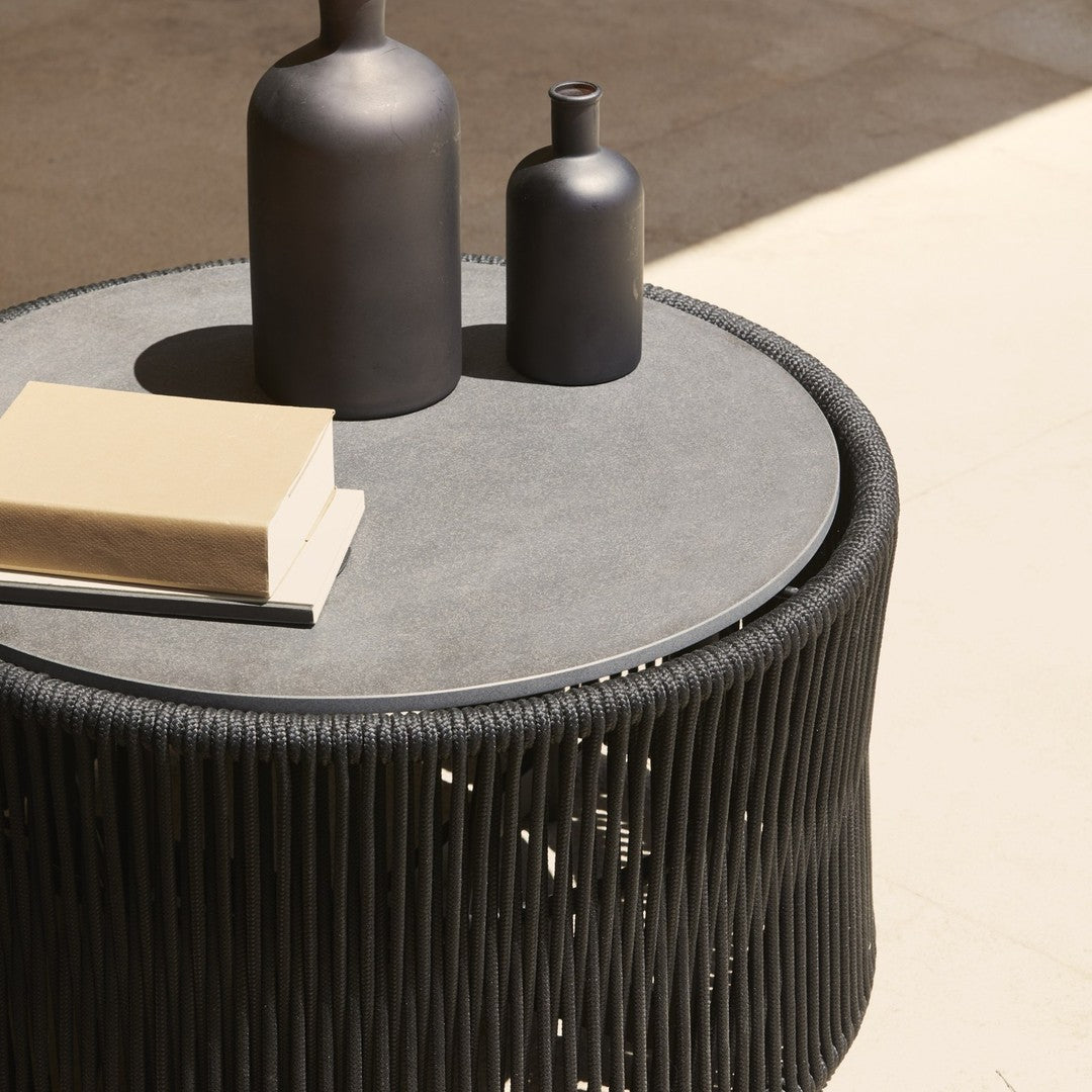 Black round table with a textured pattern, featuring a sleek gray top and minimalist decor elements in contrasting colors.