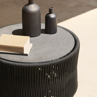 Black round table with a textured pattern, featuring a sleek gray top and minimalist decor elements in contrasting colors.