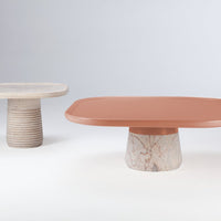 Two coffee tables featuring a soft peach top and a textured beige marble base, alongside a light grey round table.