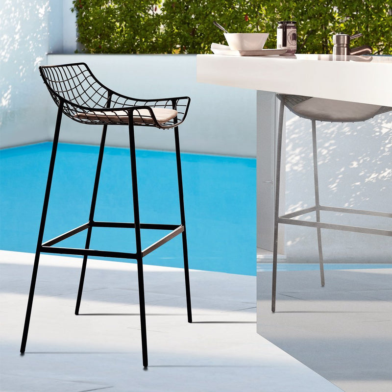 Black wire bar stool with a sleek minimalist design, set against a vibrant blue pool background.