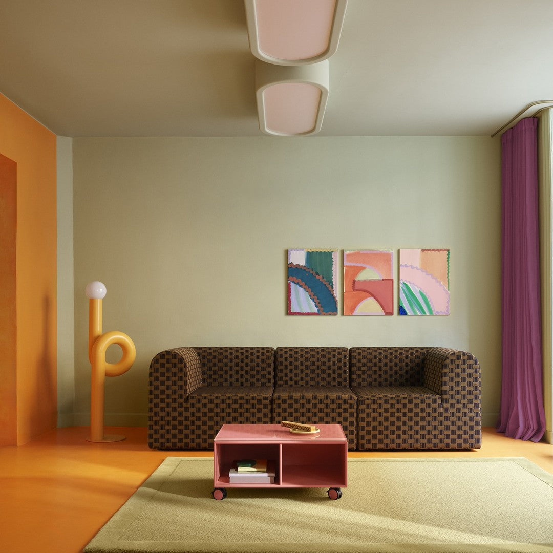 Brown polka dot sofa with purple curtains, orange accents, and colorful abstract art in a vibrant, modern living room.