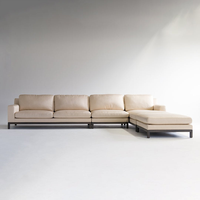 Beige sectional sofa with sleek lines and a modern design, featuring a soft fabric upholstery and dark wood legs.