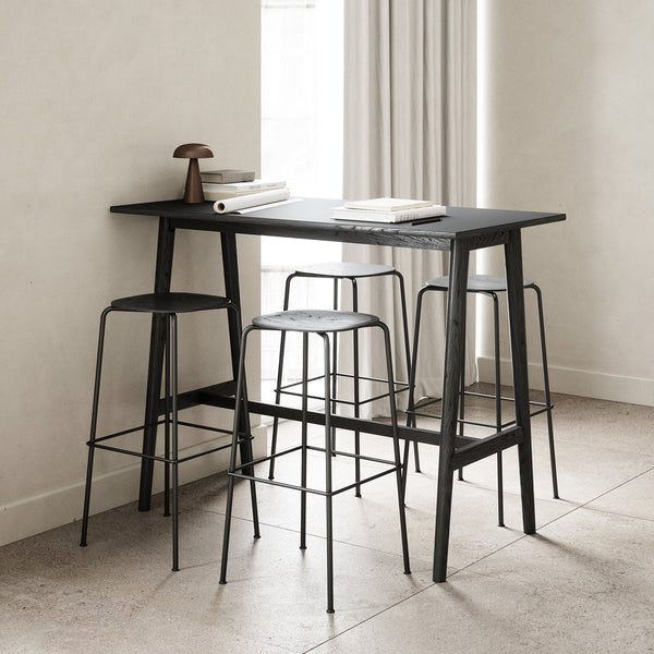 Sleek black bar table with minimalist wire stools against a light beige backdrop and neutral tones.