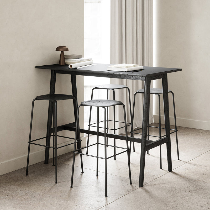 Modern black bar table and stools with sleek lines and minimalistic design against a neutral-toned background.