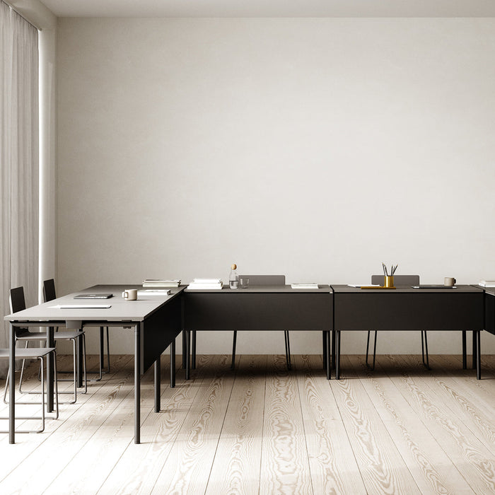 Minimalist black tables with sleek lines on light wooden flooring, creating a modern workspace aesthetic.