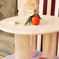 Round table with a beige top, cream honeycomb legs, striped background in pink and white, featuring an orange centerpiece.