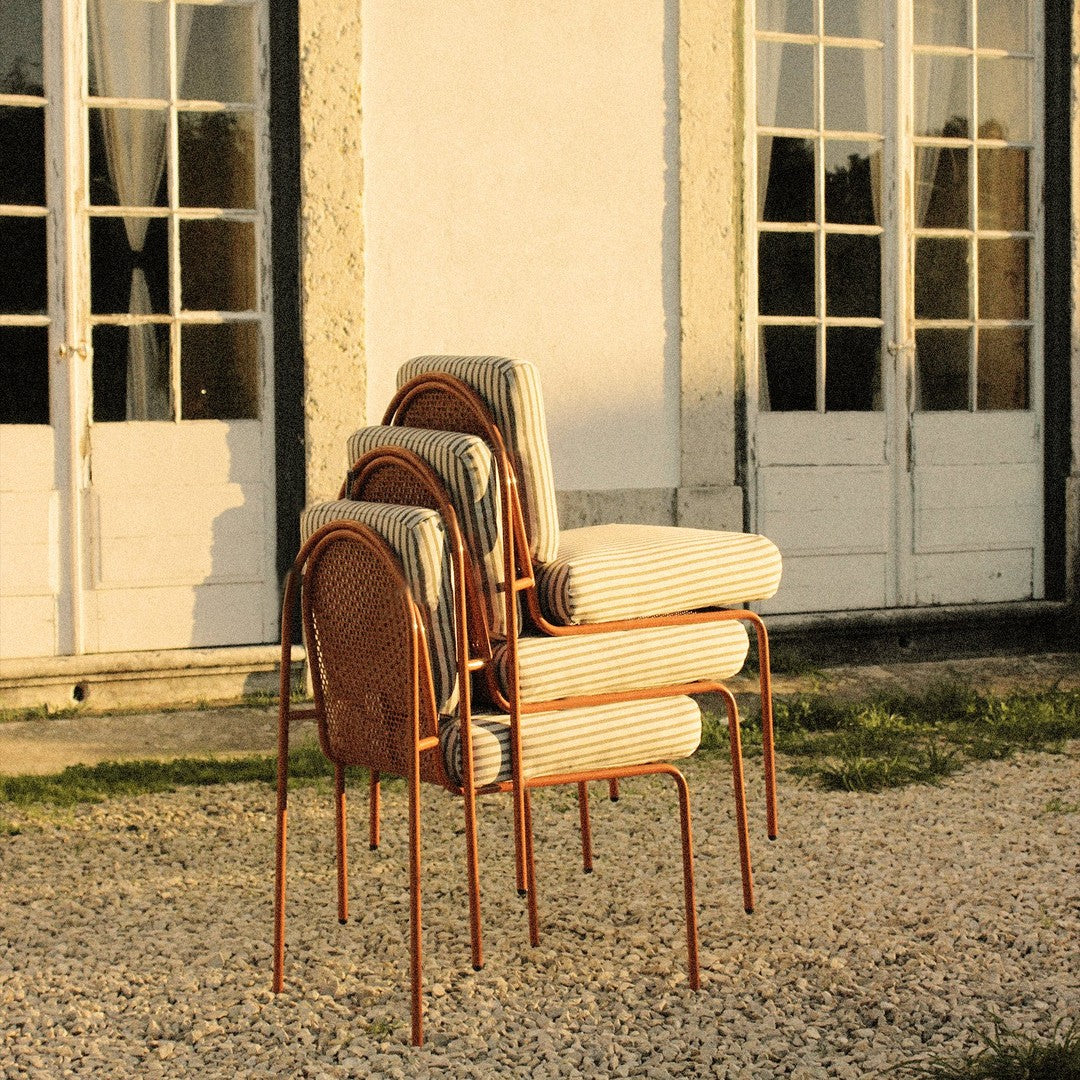 Stacked chairs featuring a rust-colored frame, with striped and solid fabric patterns in soft, neutral tones.