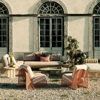 Outdoor seating in muted beige, orange, and pastel hues, featuring striped and patterned cushions. Ideal for stylish gatherings.