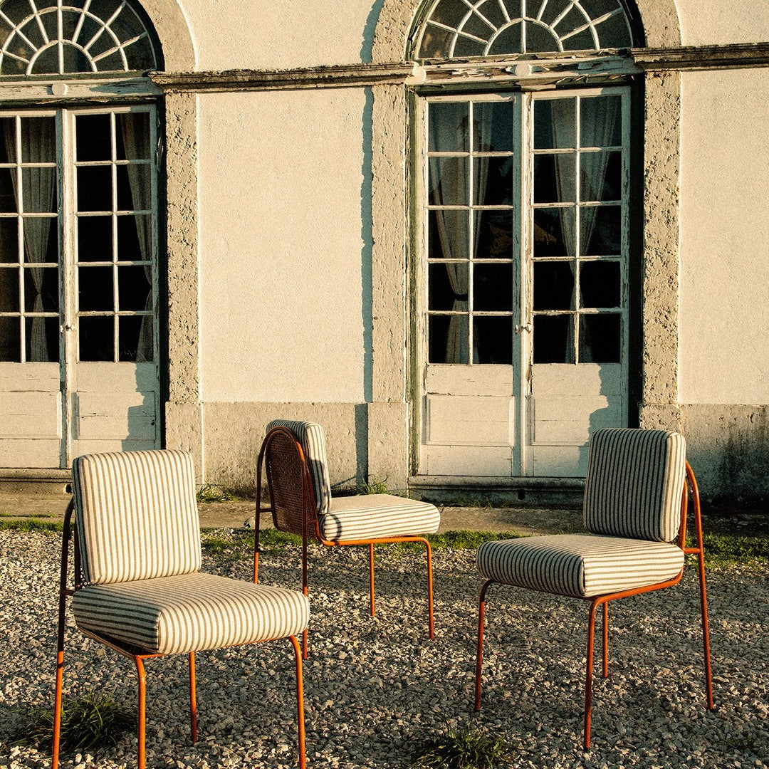 Striped beige and cream chairs with rust-colored metal frames, set against a backdrop of historic doors.